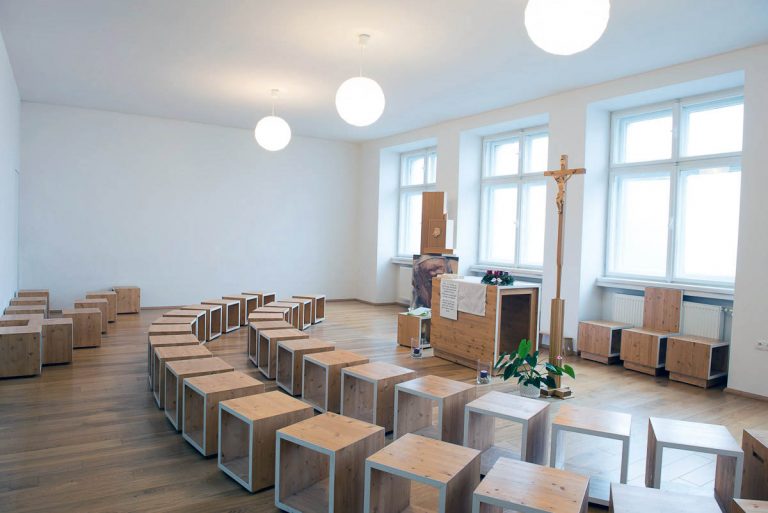 Celkový pohľad na priestor kaplnky. Priestorové obmedzenie pôvodnej školskej učebne bolo pretvorené v otvorený, čistý priestor s jasne čitateľným zariadením.