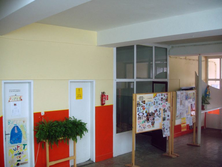 Foto pôvodného stavu. Pohľad zo vstupnej haly školskej budovy na prízemí. Dverami v presklennej stene sa žiaci dostávali cez šatňu do svojej triedy, učebne.